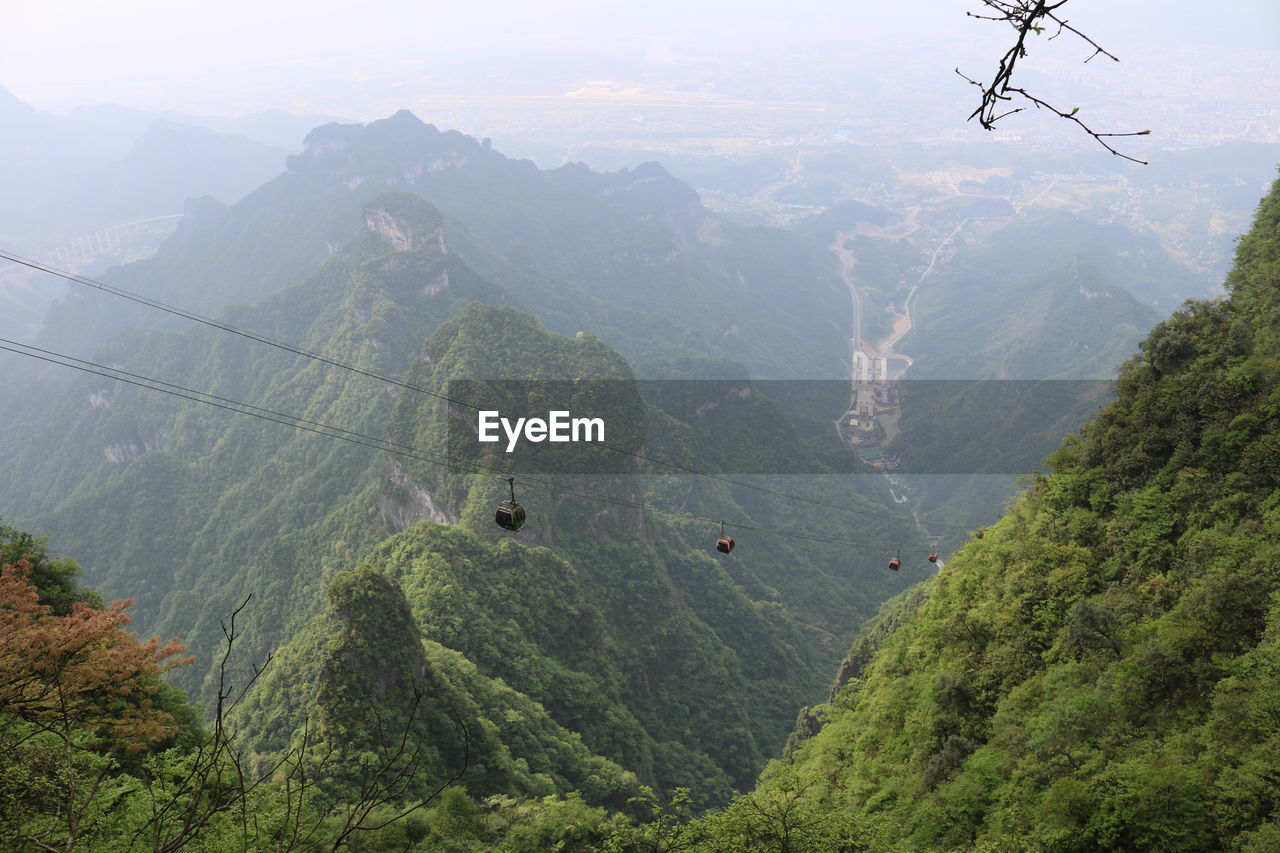 HIGH ANGLE VIEW OF OVERHEAD CABLE CAR AGAINST MOUNTAINS