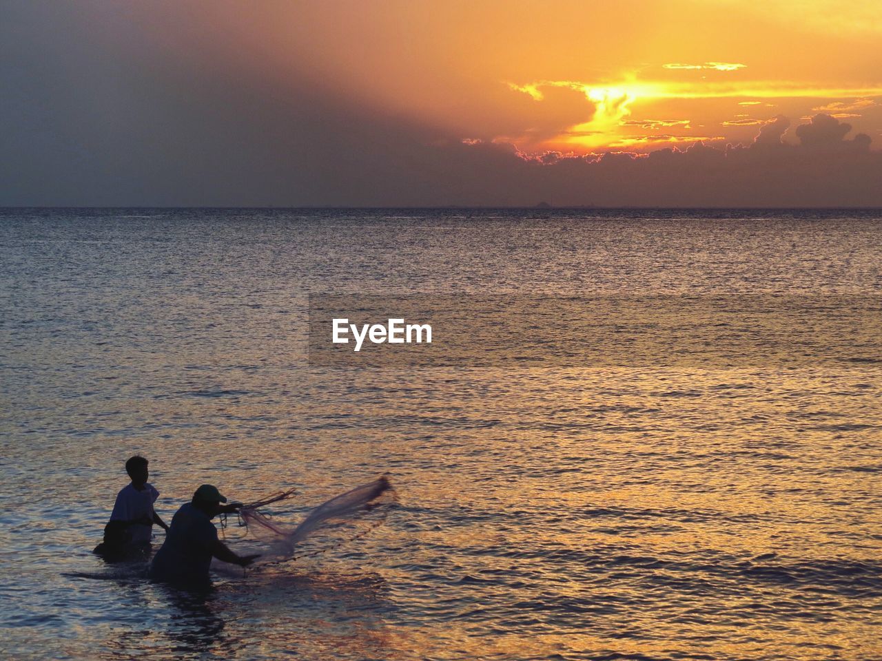 SILHOUETTE PEOPLE AT SEA AGAINST SKY DURING SUNSET