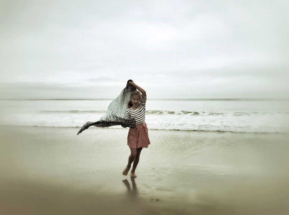 Portrait of cheerful girl with scarf on beach