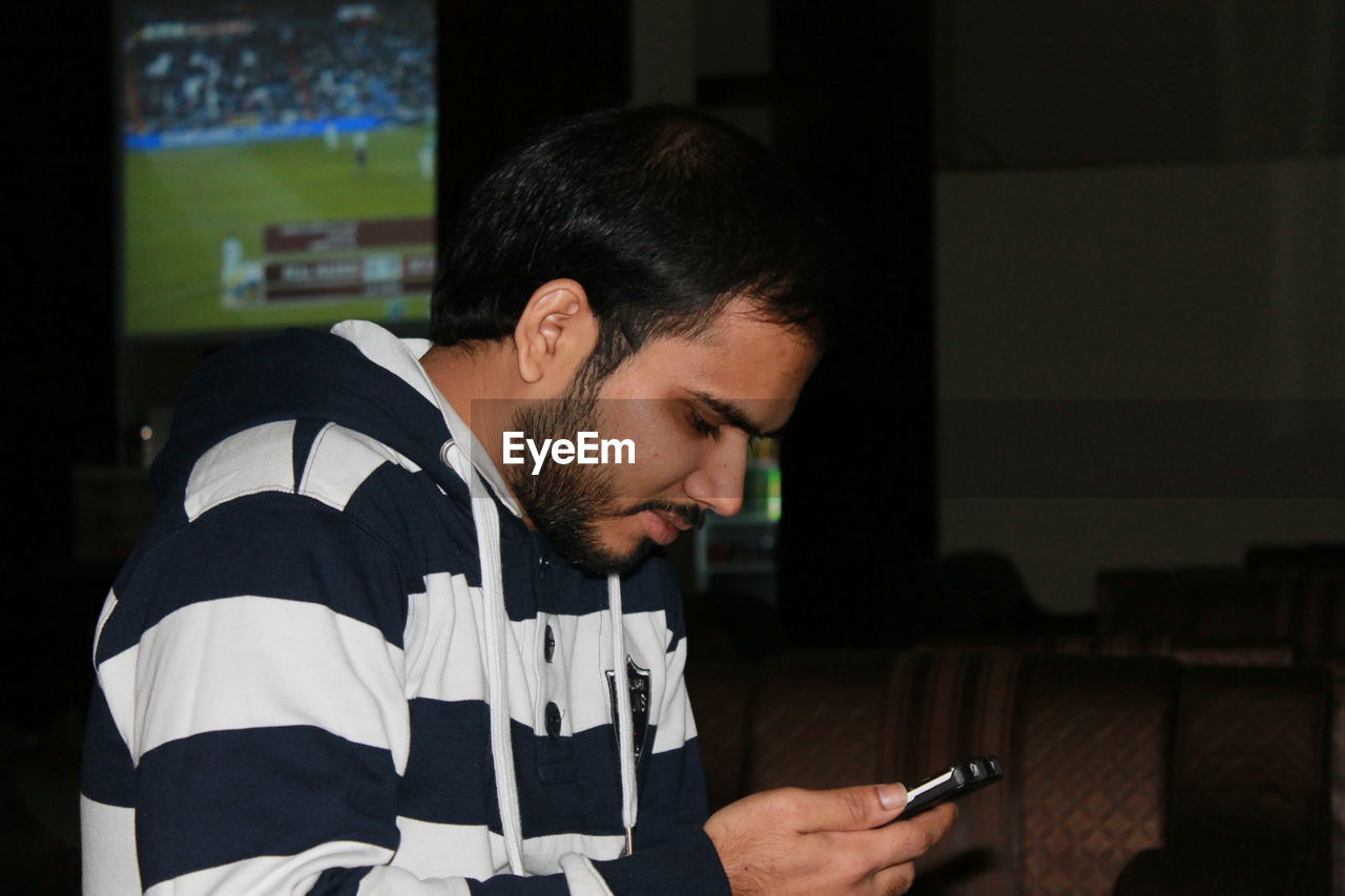 Close-up of young man using smart phone while sitting at home