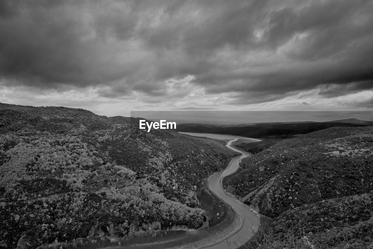 cloud, environment, road, landscape, sky, black and white, transportation, monochrome, nature, scenics - nature, horizon, monochrome photography, beauty in nature, winding road, mountain, no people, curve, land, dramatic sky, travel, plant, outdoors, non-urban scene, cloudscape, overcast, tranquility, coast, storm, travel destinations, day, darkness