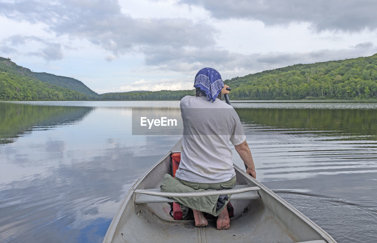 Barefoot paddler on a calm lake on lake of the clouds in porcupine mountains state park in michigan