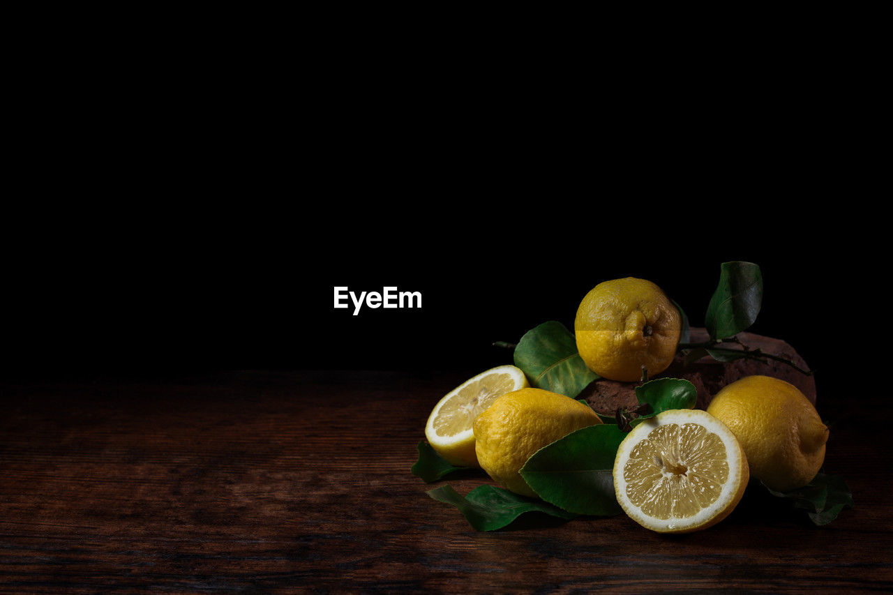 Still life of lemons on wooden table with black background
