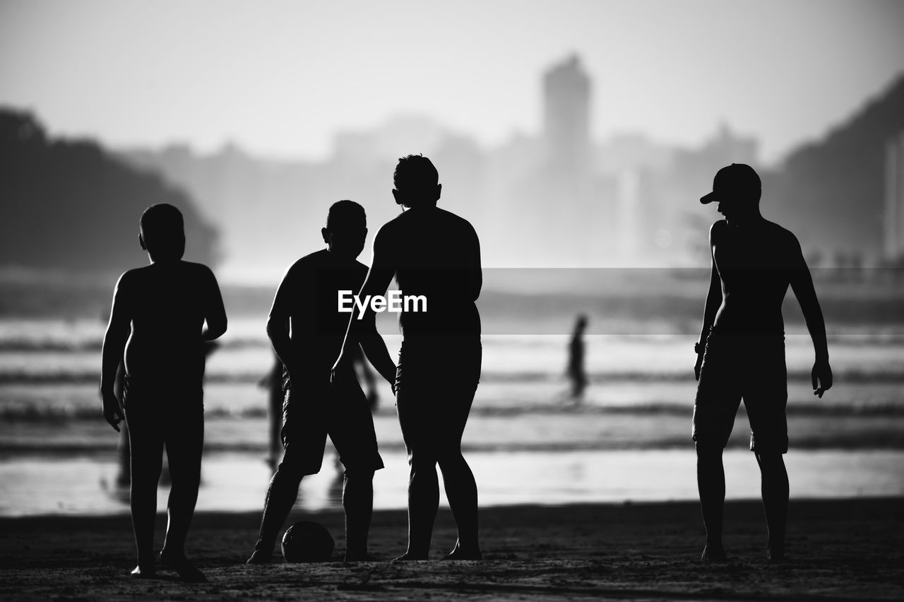 Silhouette people on beach against sky during sunset