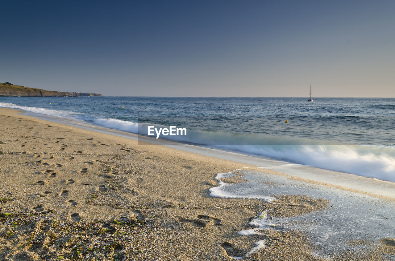 SCENIC VIEW OF BEACH AGAINST CLEAR SKY DURING SUNRISE