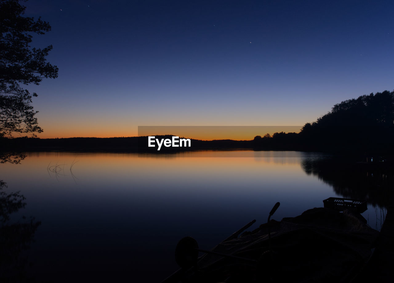 SCENIC VIEW OF LAKE AGAINST CLEAR SKY AT SUNSET
