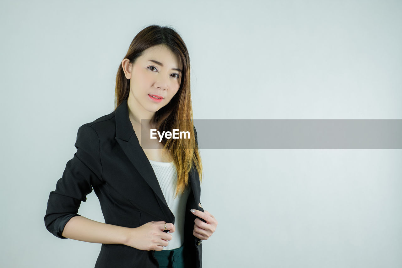 PORTRAIT OF YOUNG WOMAN AGAINST WHITE BACKGROUND