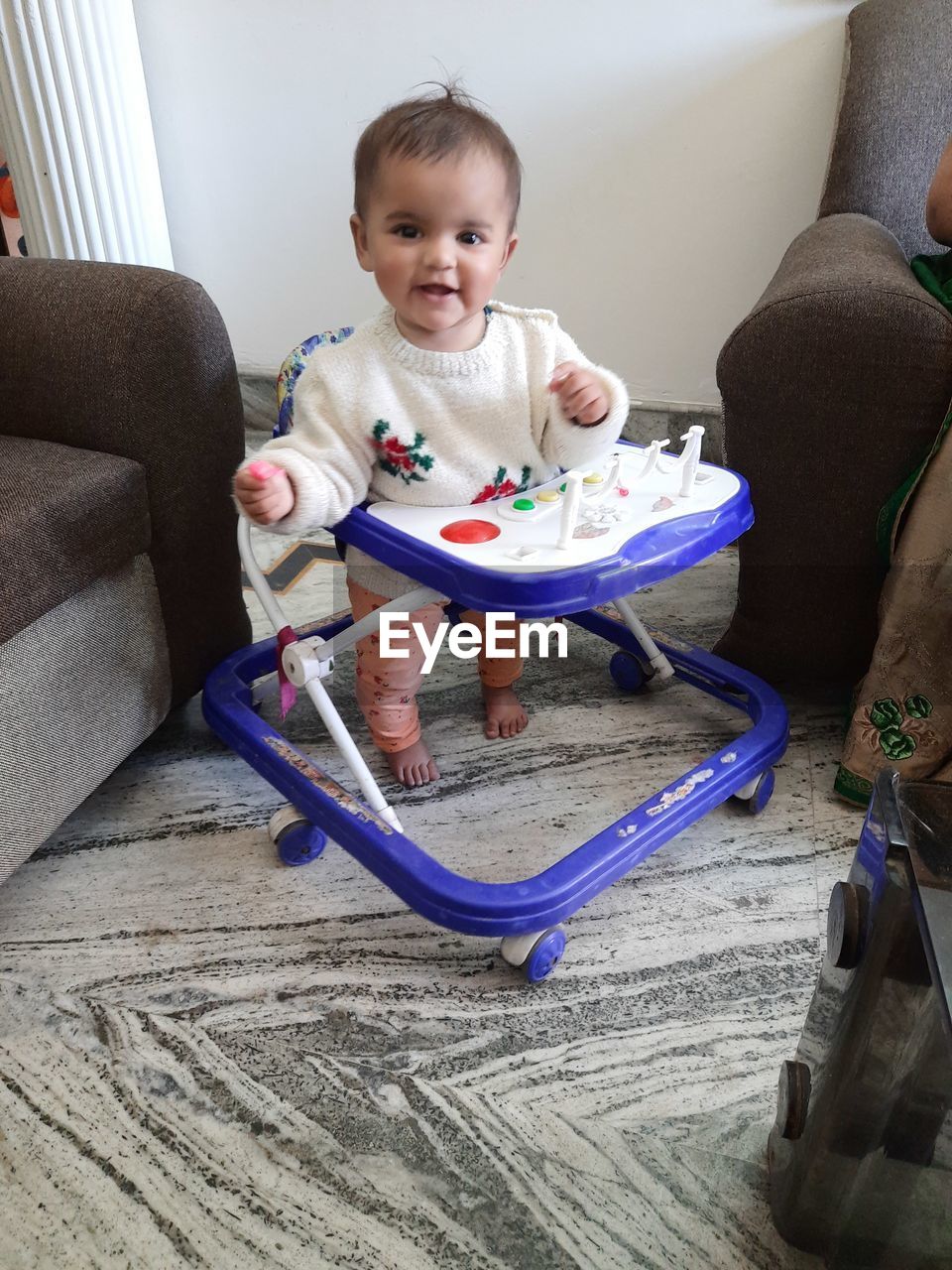 Portrait of cute baby girl standing in walker at home