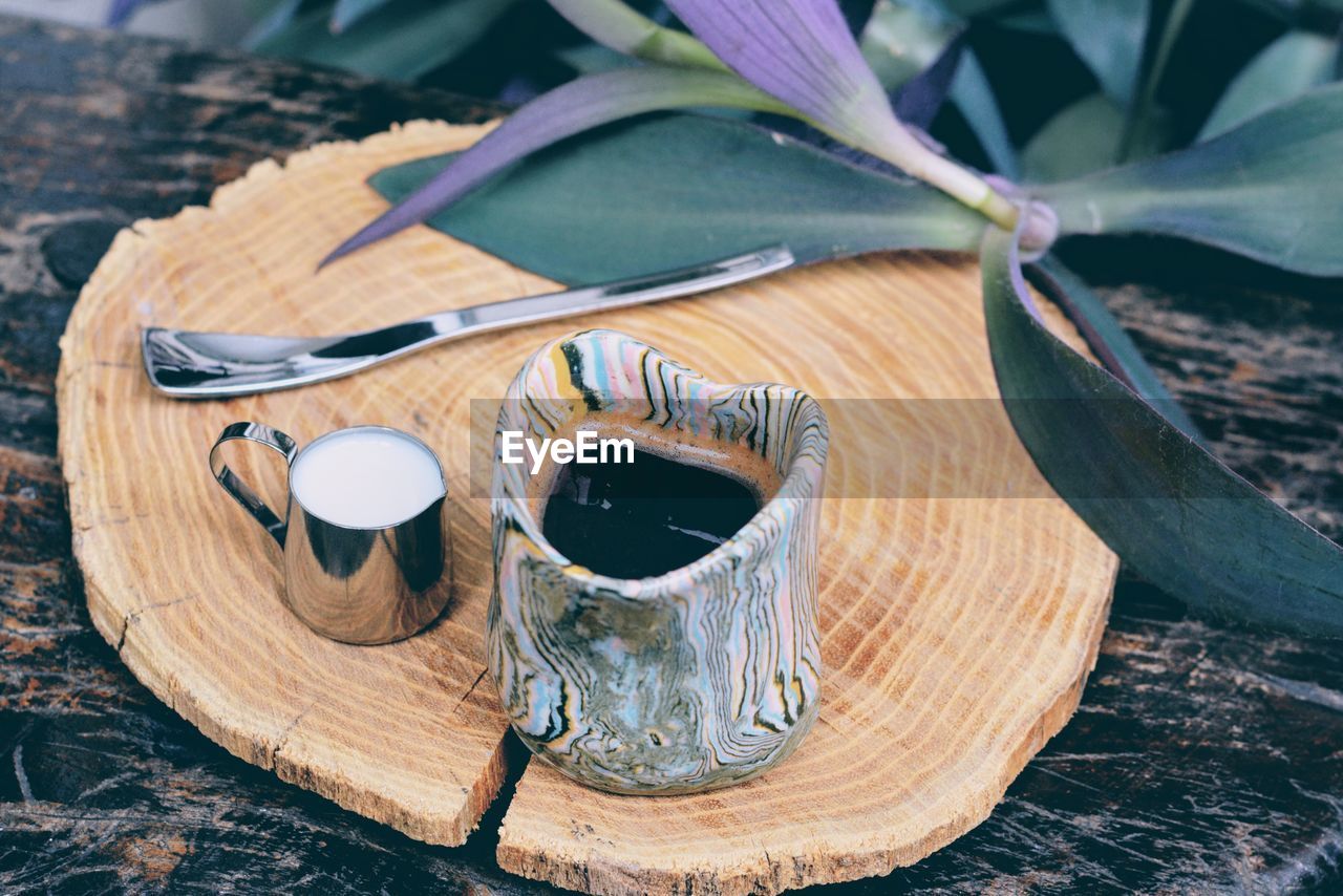 Black coffee and milk in mug on cutting board