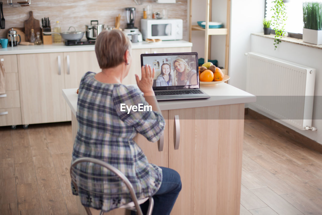 Woman video conferencing over laptop at home