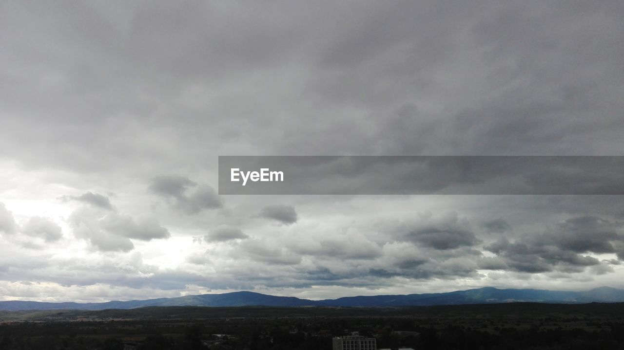 STORM CLOUDS OVER LANDSCAPE AGAINST SKY