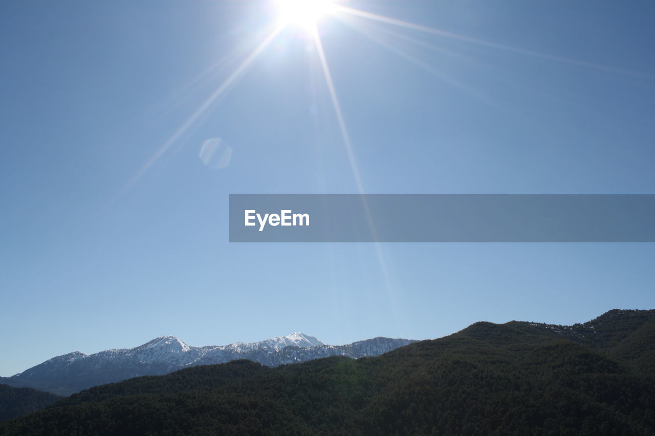 Scenic view of mountains against clear sky on sunny day