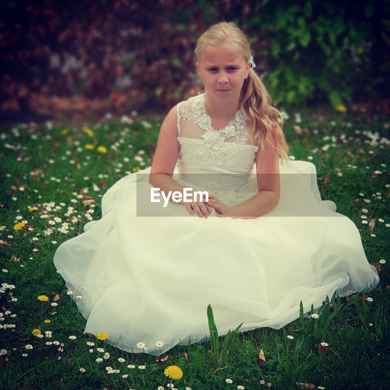 Portrait of girl in gown sitting on field