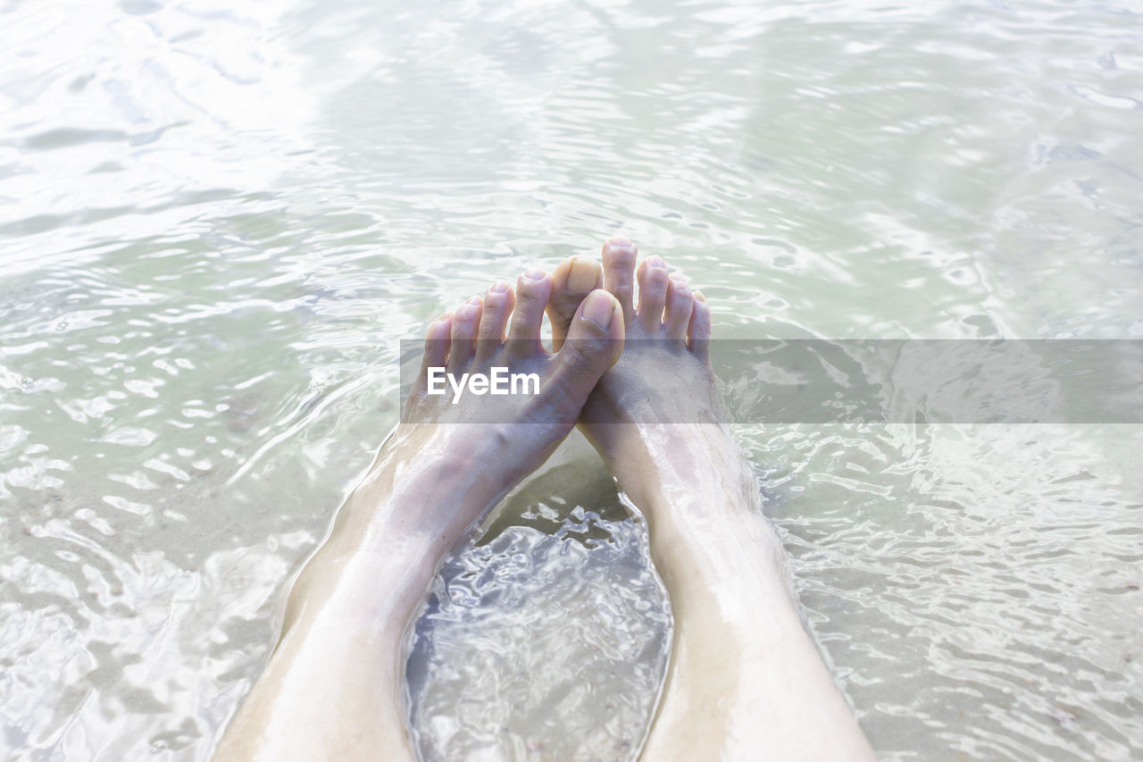 LOW SECTION OF PERSON RELAXING ON SWIMMING POOL