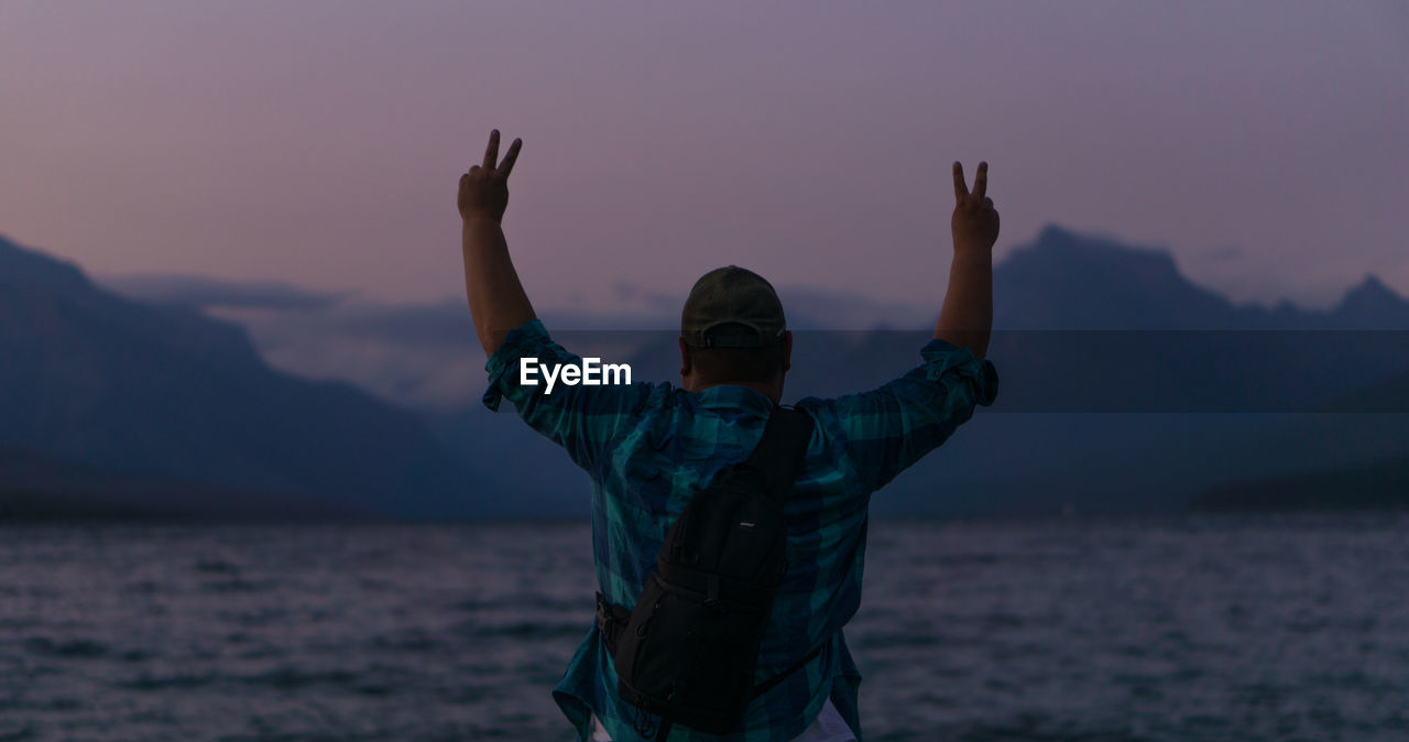 Man standing by sea against sky during sunset