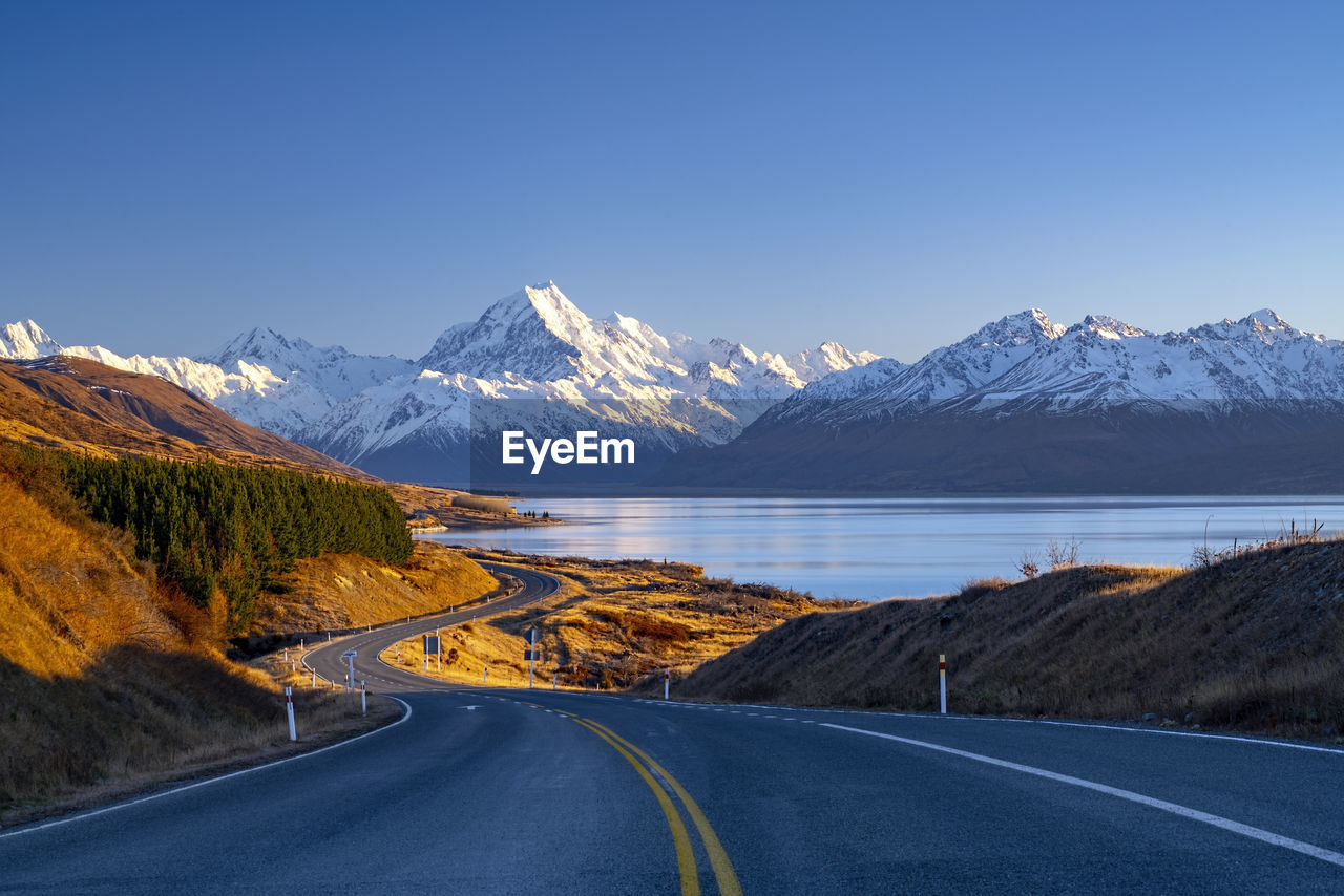 Road by snowcapped mountains against sky