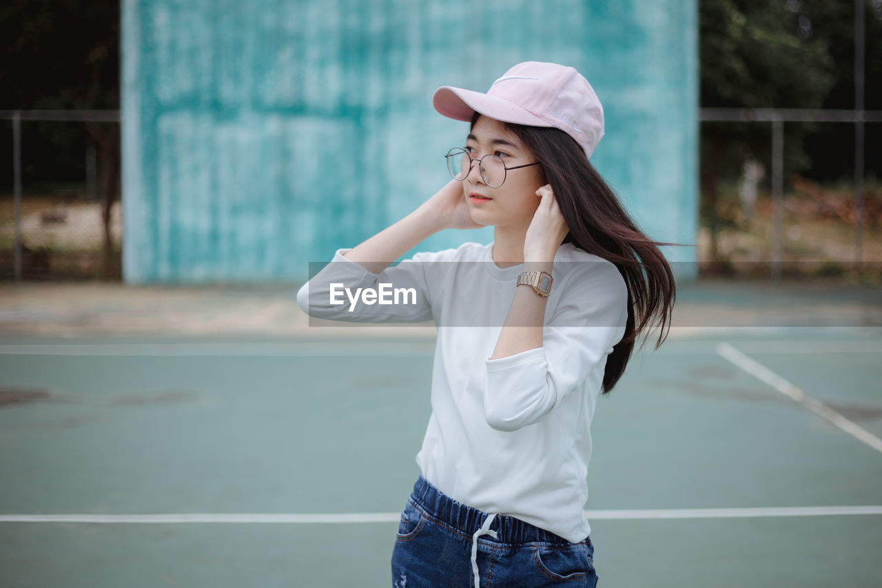 Beautiful young woman standing on tennis court