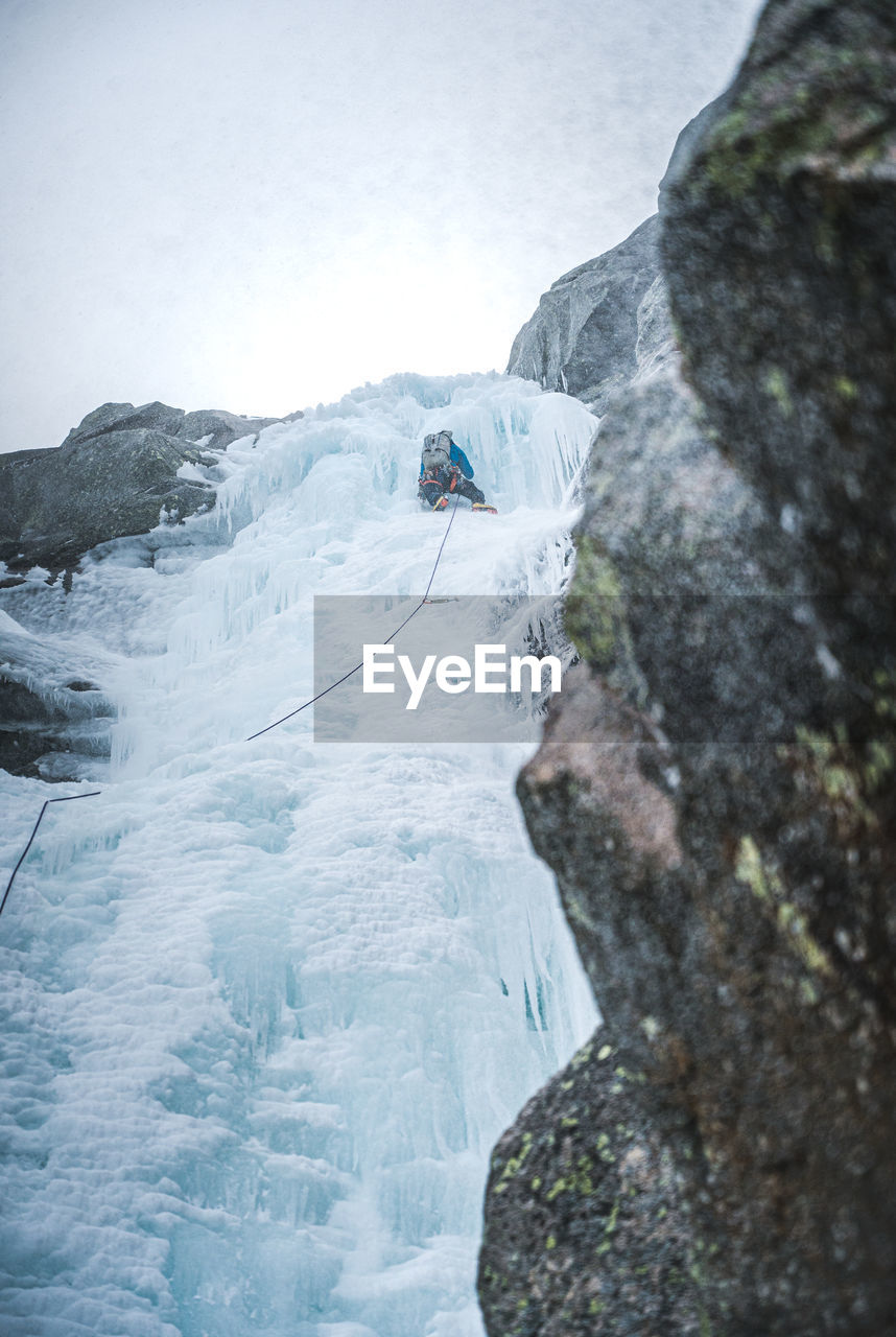 An ice climber climbs up a steep gully full of ice in maine alpine