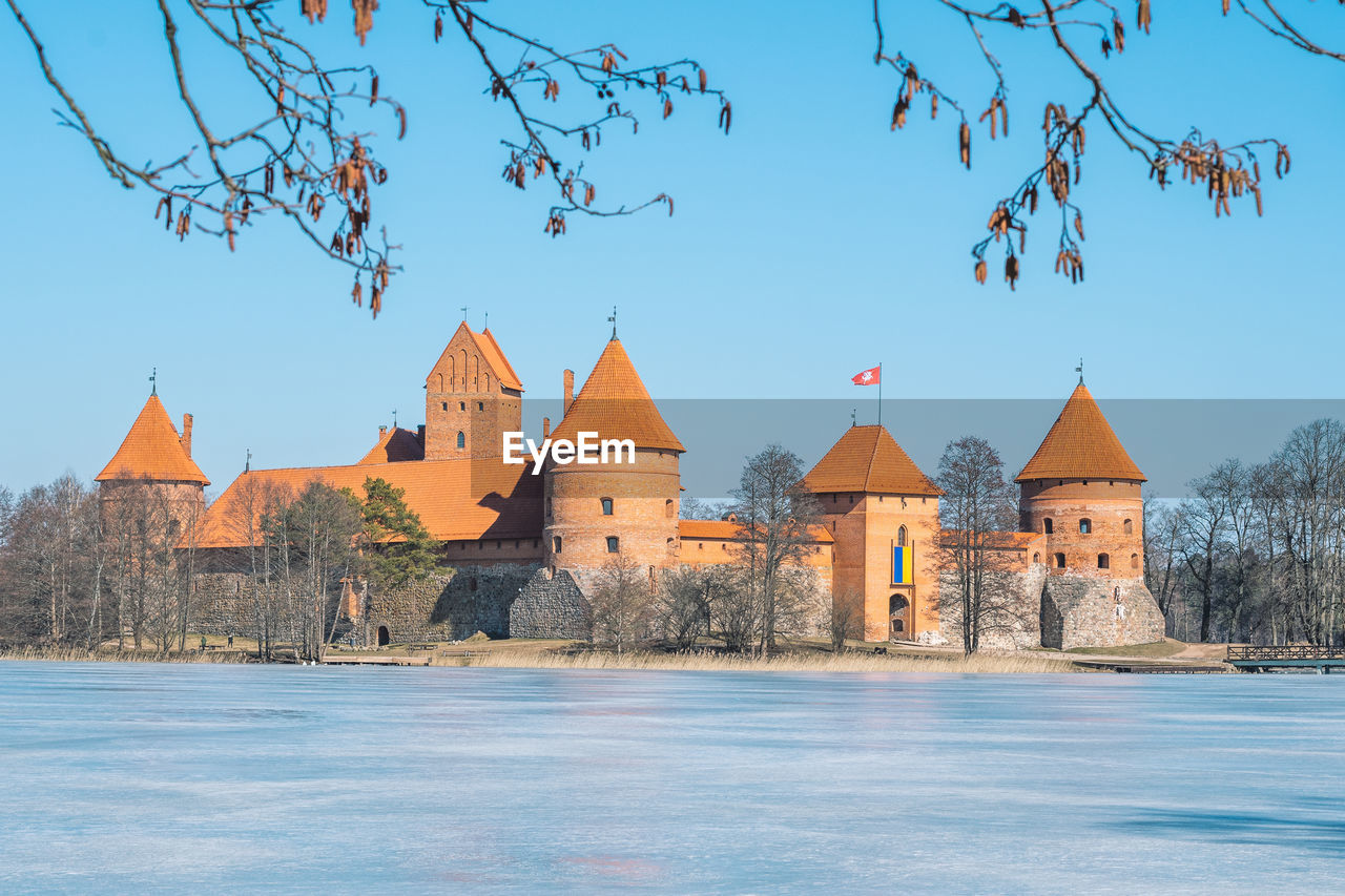 Medieval castle of trakai, vilnius, lithuania in winter with frozen lake and ukrainian flag