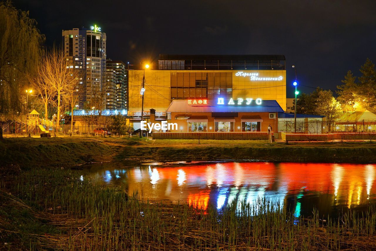 REFLECTION OF ILLUMINATED BUILDING IN WATER