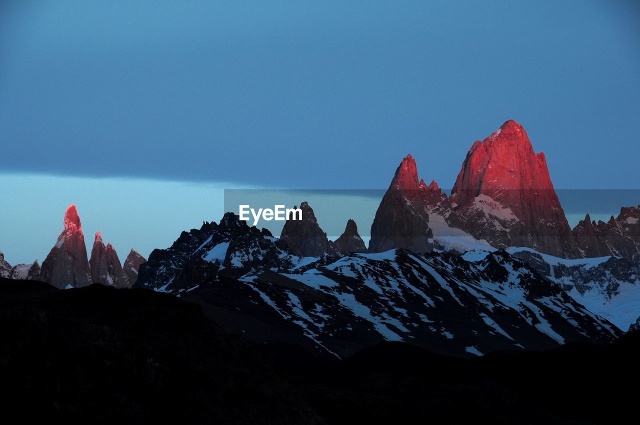 Scenic view of snowcapped mountains against blue sky at dawn