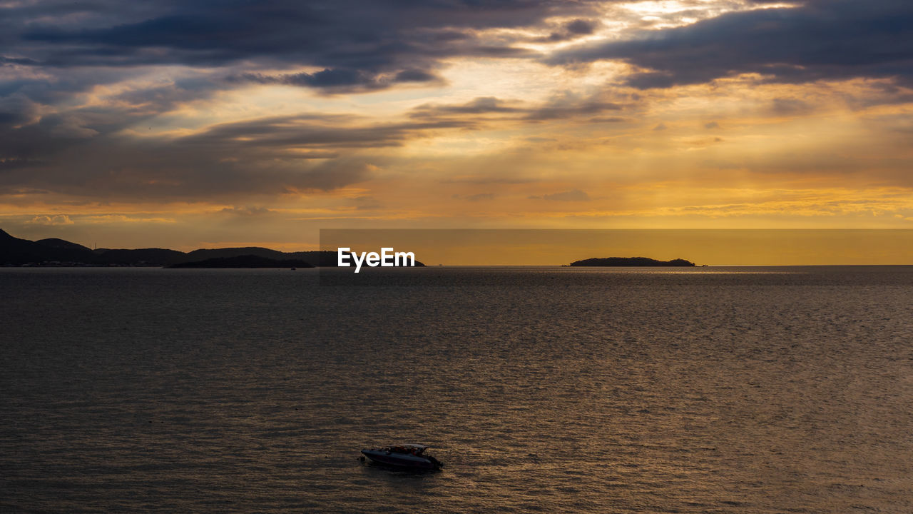 Silhouette of a boats in the middle of the ocean with dramatic sunset sky color.