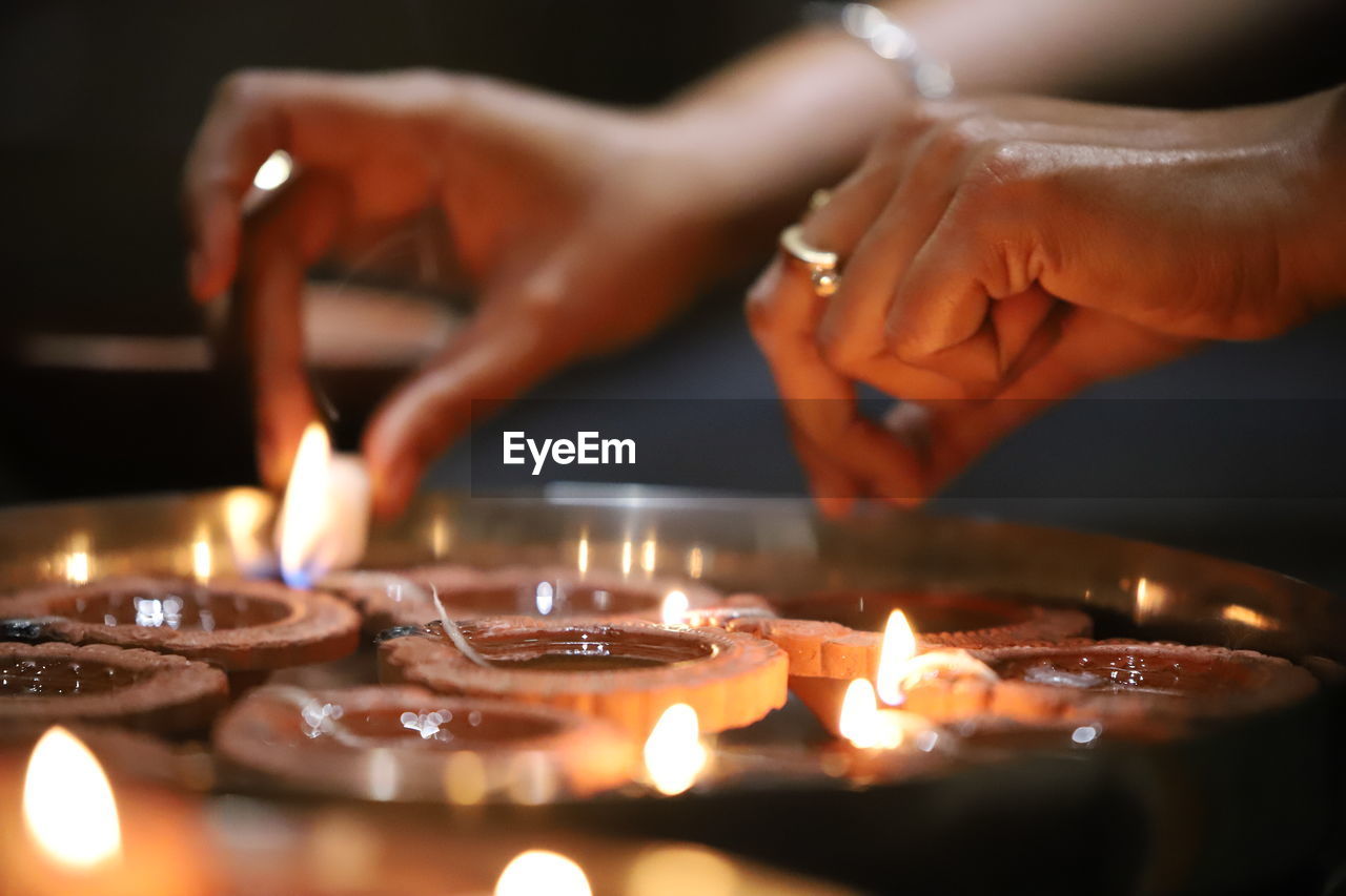 Close-up of woman hand with illuminated diyas