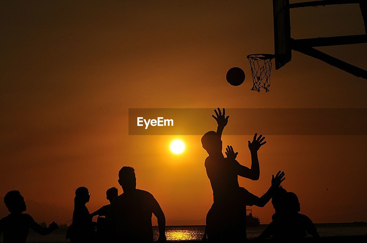 Silhouette of people playing basketball