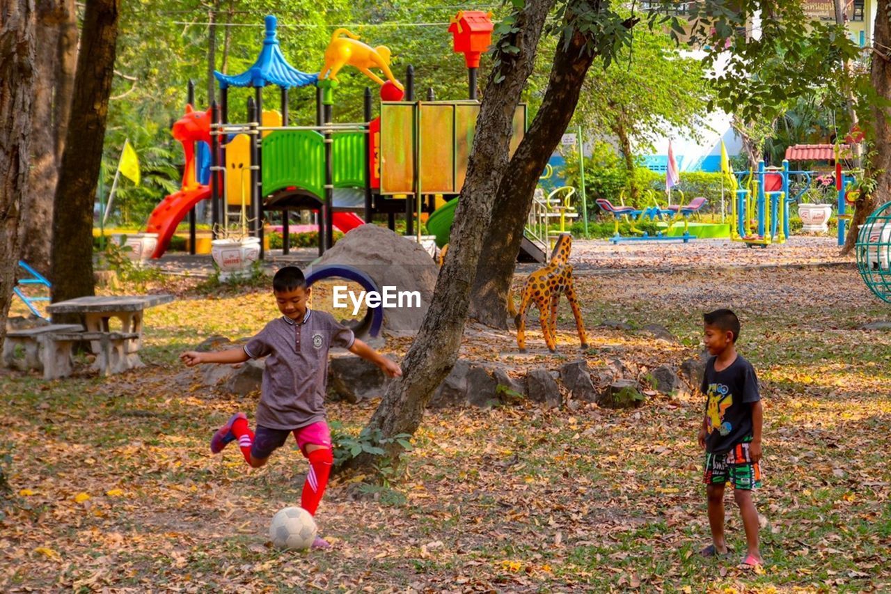 Full length of cheerful friends playing with ball in park