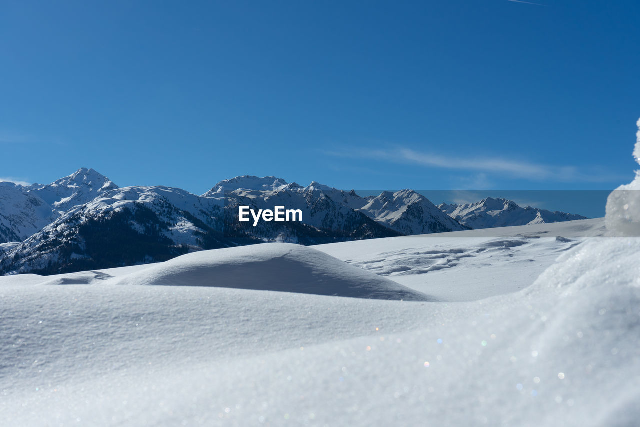 Scenic view of snowcapped mountains against blue sky