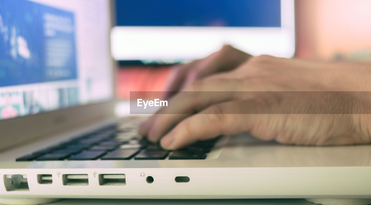 Close-up of man typing on laptop keyboard