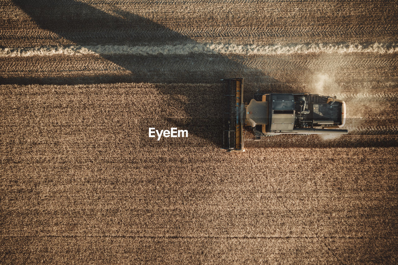 Combine harvester working at sunset from aerial view.