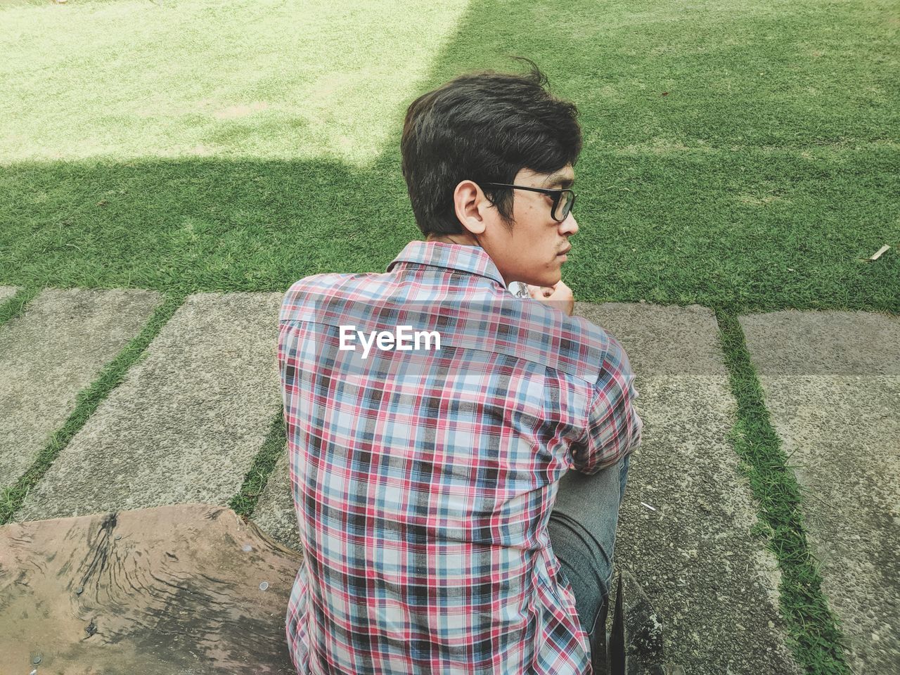 Rear view of man looking away while sitting outdoors