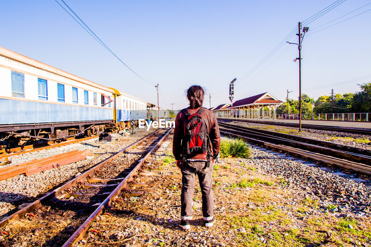 Rear view of man standing on railroad track