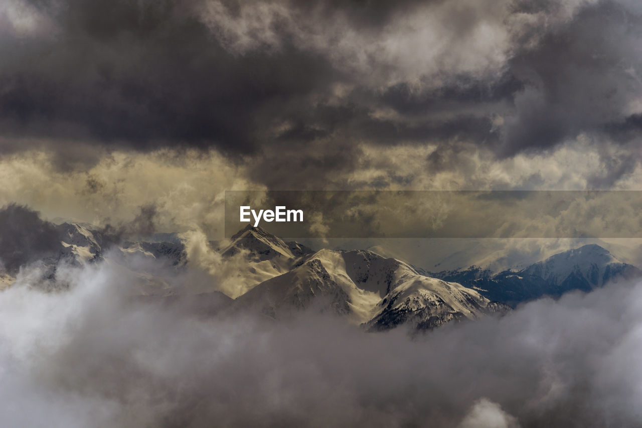 Aerial view of snowcapped mountains against cloudy sky