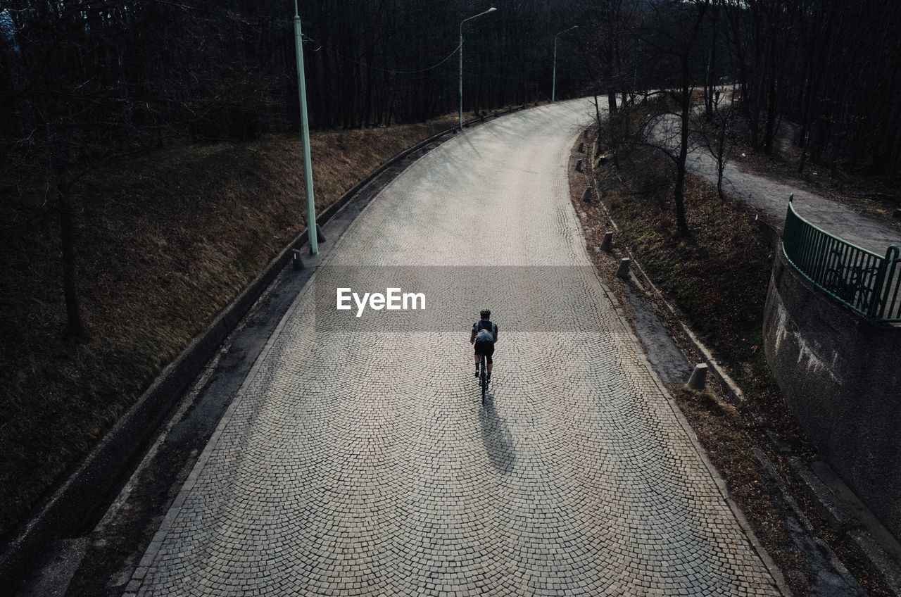 Rear view of man riding cycle on road