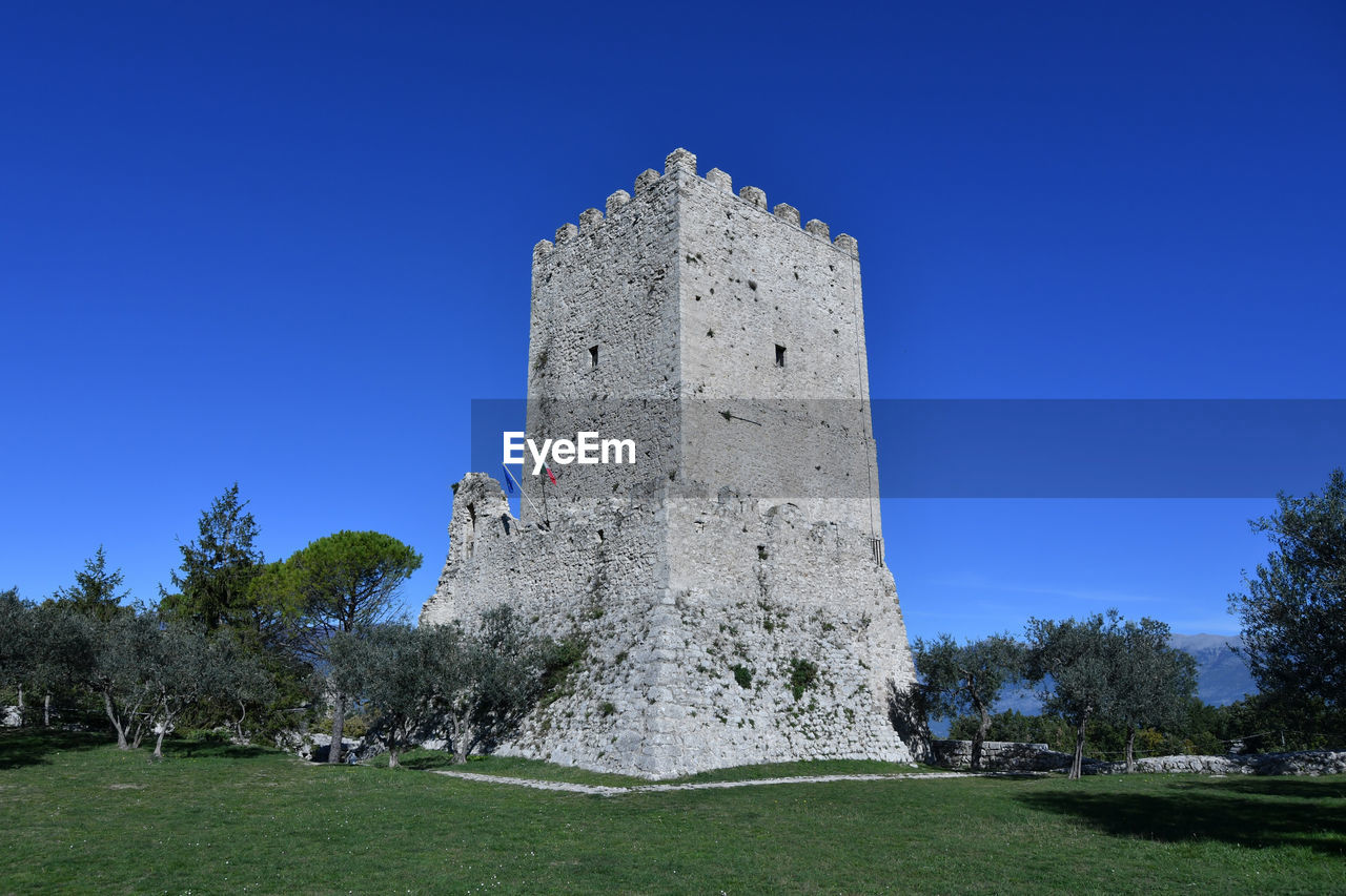 architecture, sky, plant, history, the past, built structure, grass, blue, nature, tree, landmark, clear sky, travel destinations, building, building exterior, castle, no people, travel, tower, château, outdoors, day, sunny, land, tourism, ancient, landscape, fort, monument, old, old ruin, field