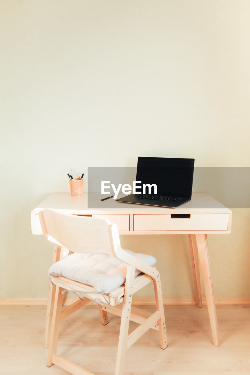 Black laptop on wooden table in home interior. empty wall with copyspace. 