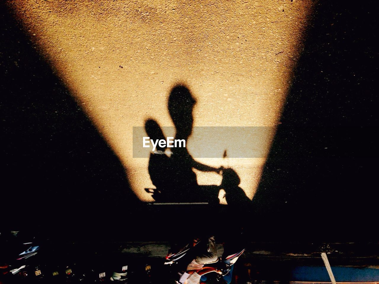 Shadow of people riding motor scooter
