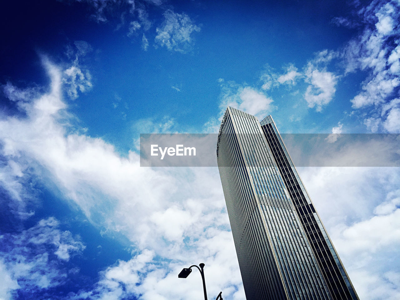 Low angle view of modern building against cloudy sky