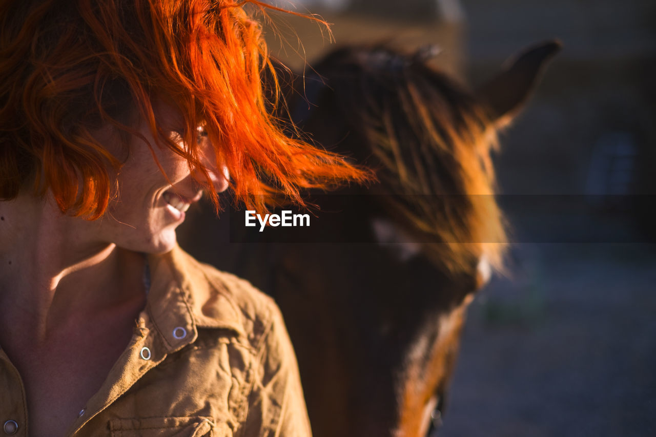 Smiling woman standing by horse