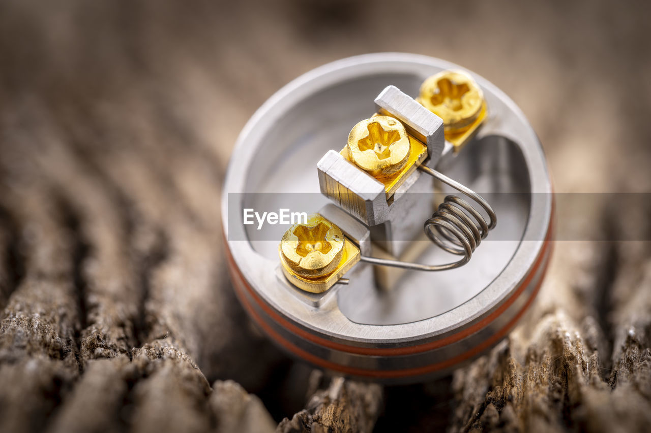 Single space coil in rebuildable dripping atomizer on rustic wood texture background, vaping device