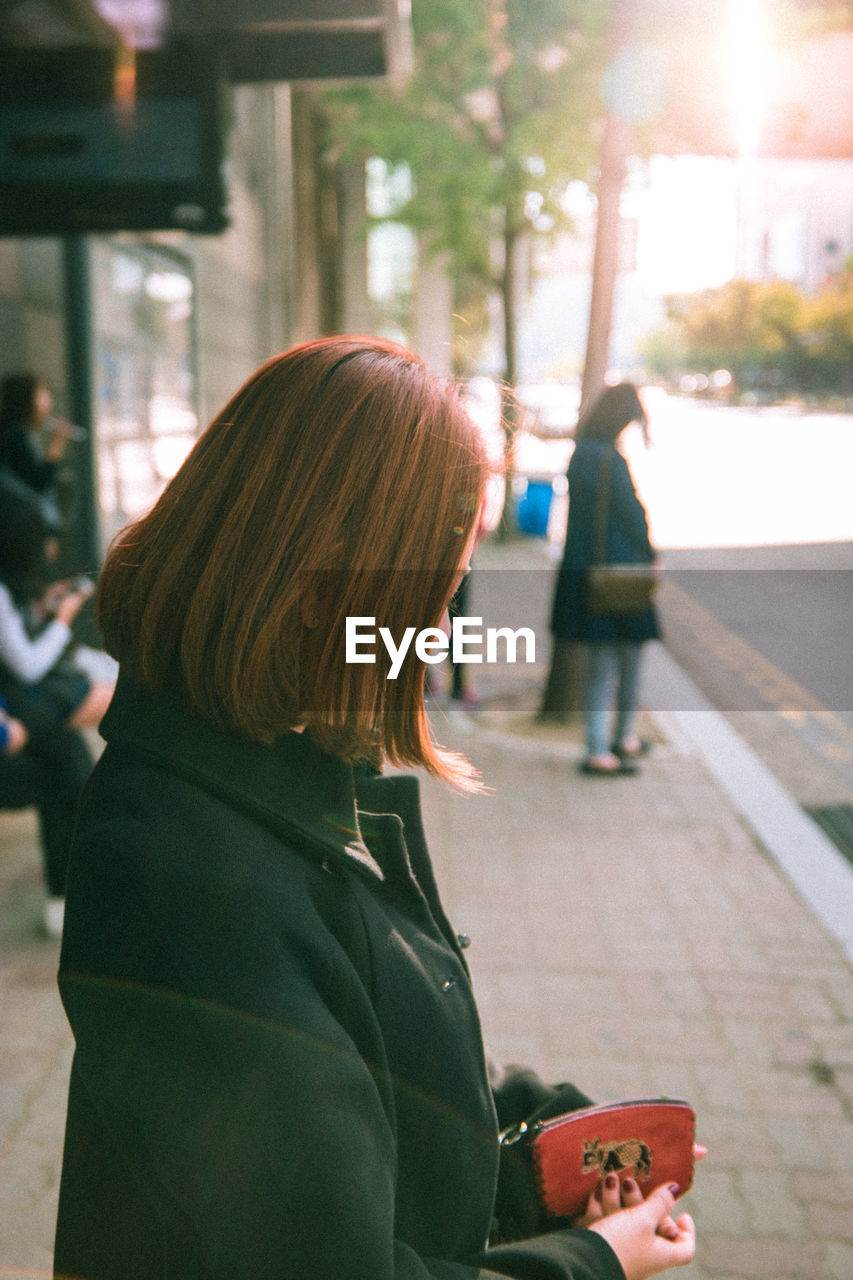 Side view of woman standing outdoors in the city