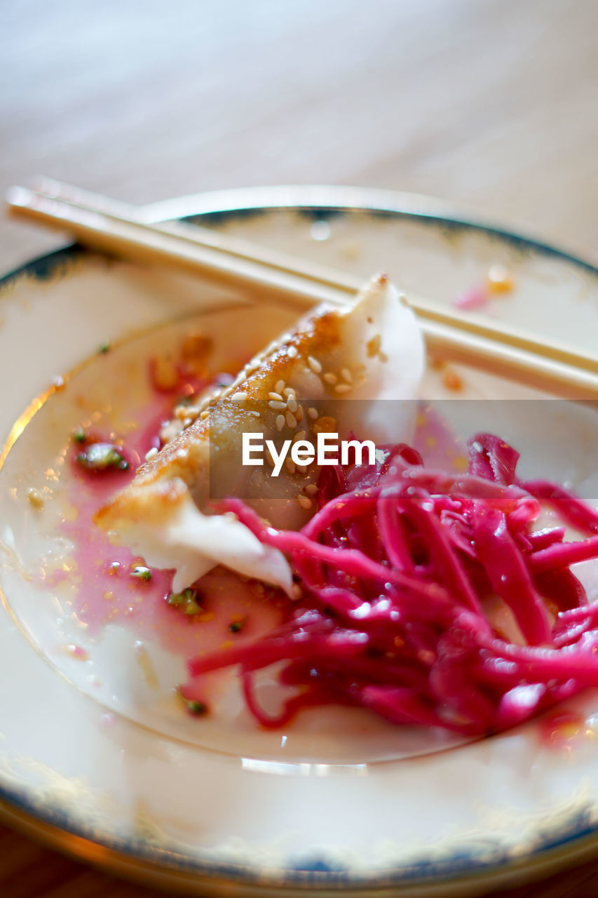 Close-up of jiaozi with red cabbage in plate on table