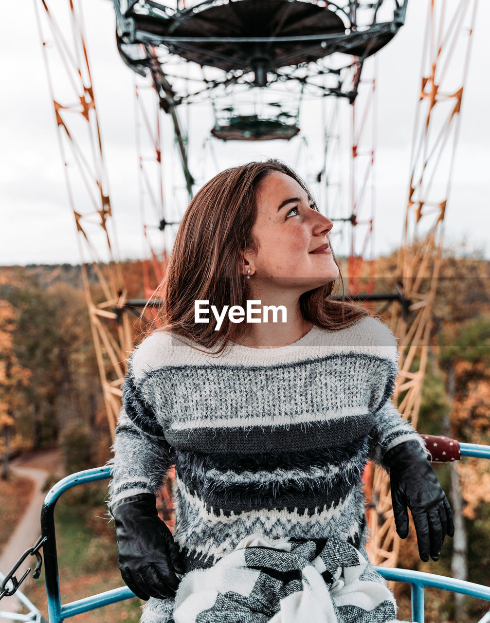 Smiling young woman looking away while sitting on ferris wheel