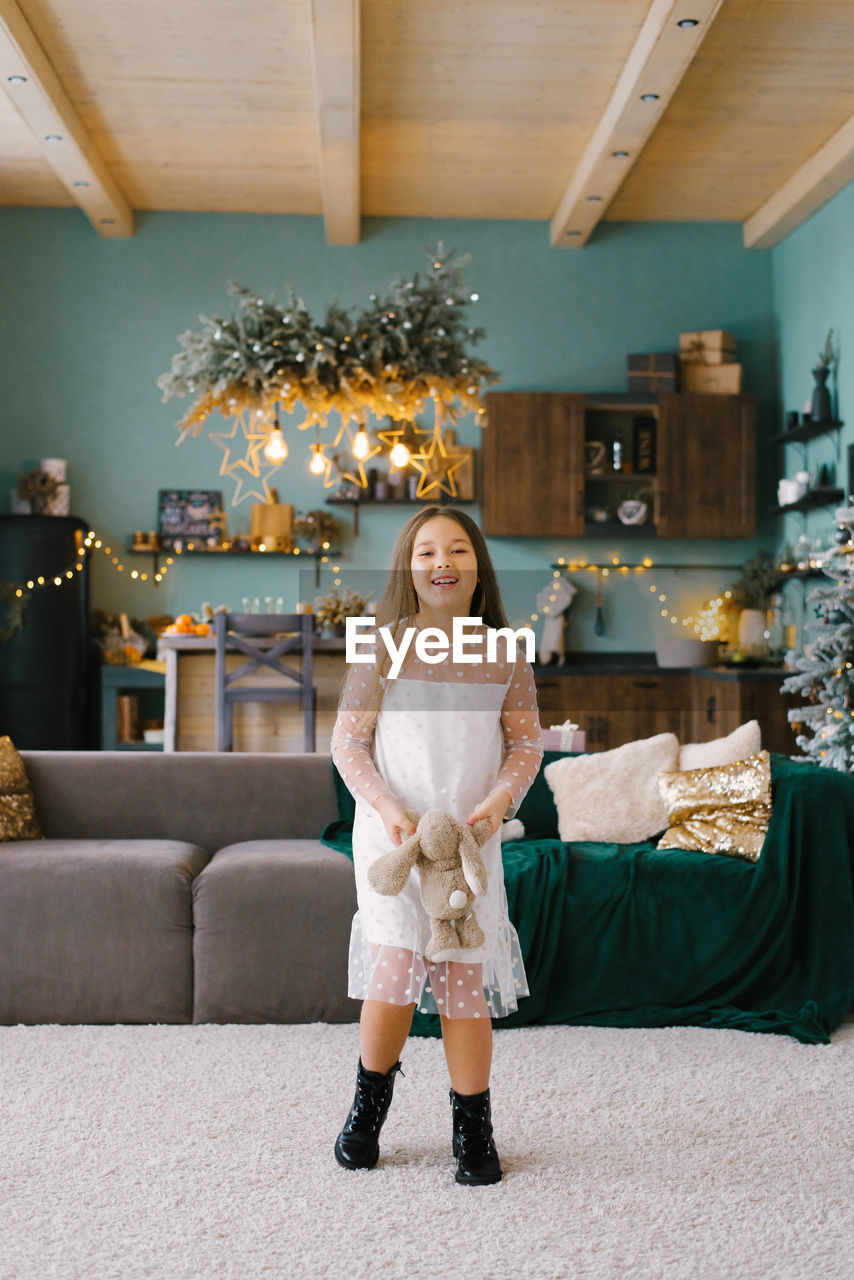 A girl has fun with a stuffed toy in the living room, decorated for christmas