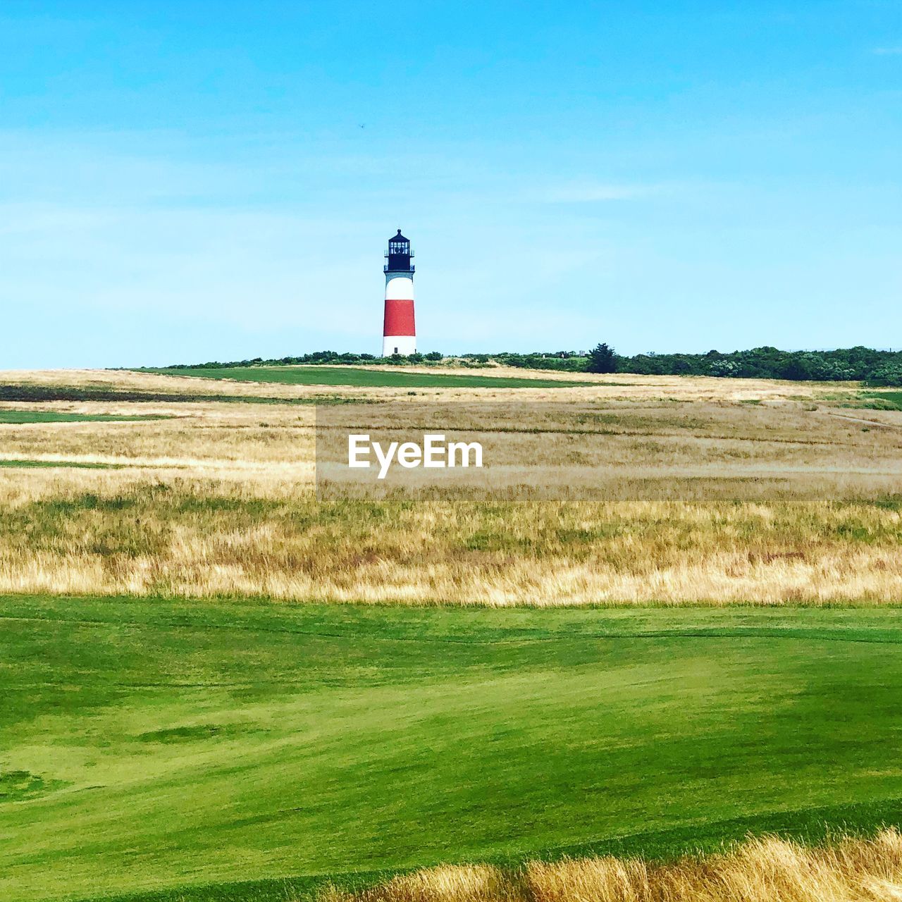 Lighthouse on field against sky