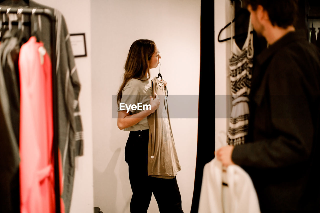 Side view of woman with clothing in retail store