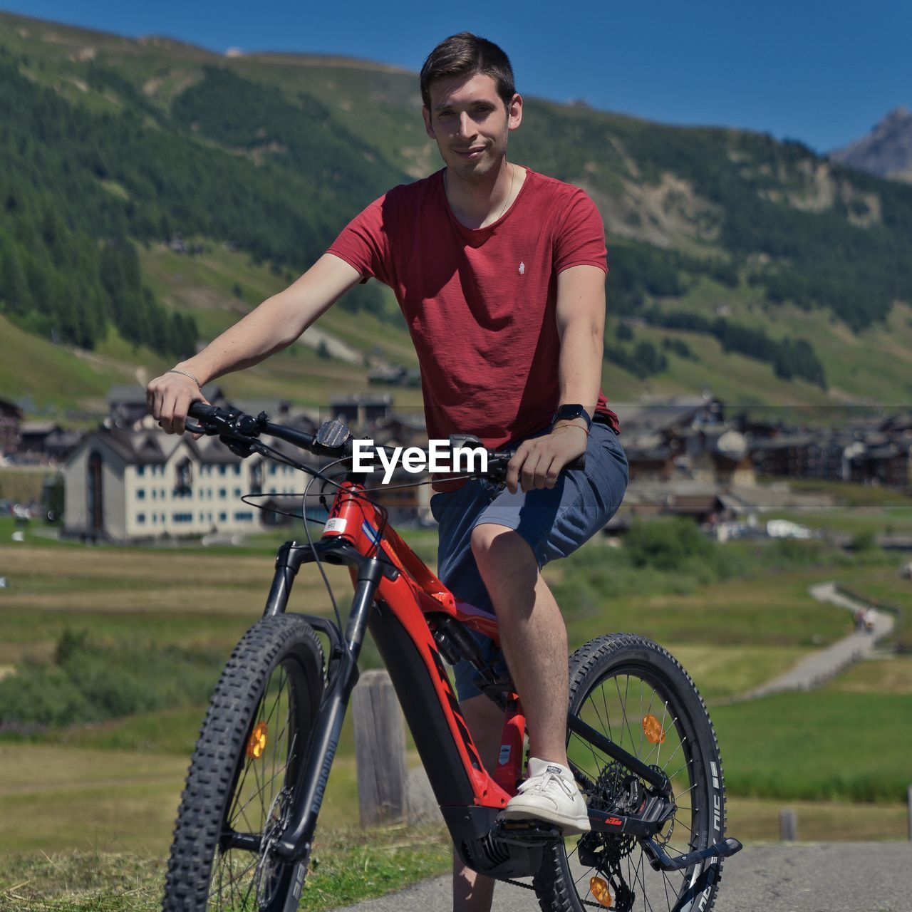 A man riding a bicycle on the street with a mountain backdrop