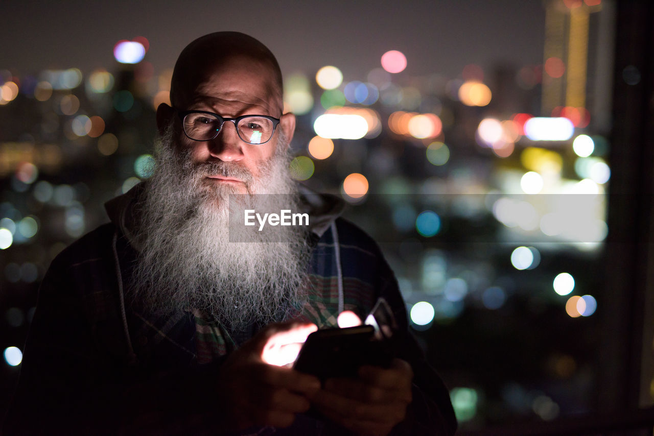 Portrait of man using mobile phone at night